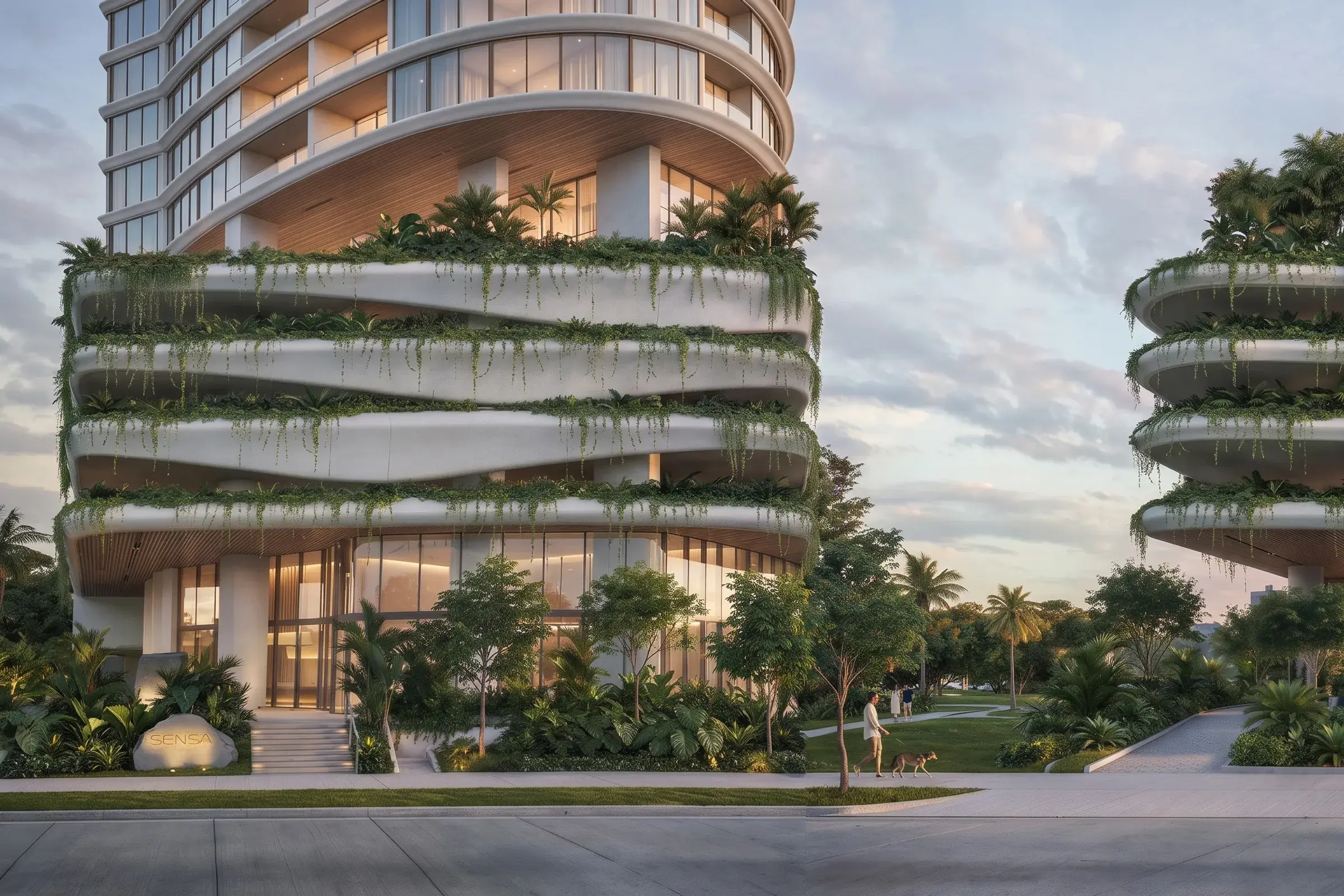 Architectural render of the Sensa Residences entrance at dusk, with curved, planted terraces wrapping the lower floors, a SENSA stone sign by the steps and a tree-lined sidewalk.