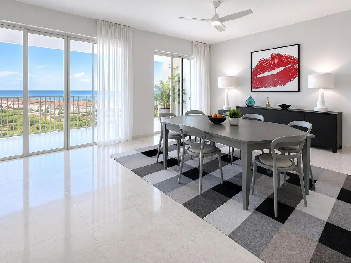 Mesa de comedor en Puntarena Ocean Village junto a puertas corredizas de piso a techo con vista sobre casas de techo rojo hacia el mar.