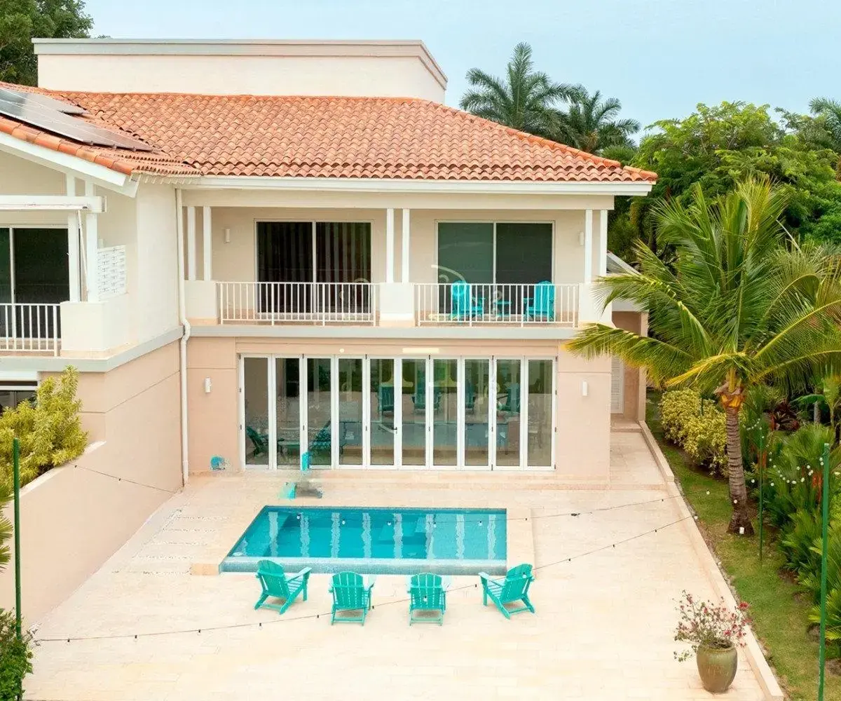 Back of the two-level Ocean Lakes villa with a clay tile roof, upstairs balconies and folding glass doors onto the pool terrace.